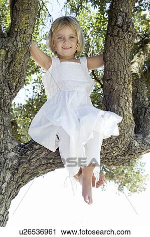 Stock Image - Girl sitting in a tree. Fotosearch