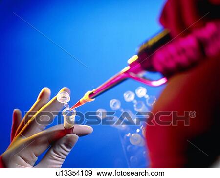 Stock Photo - Gloved hands pipetting a liquid into a vial. Fotosearch