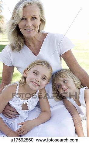 Stock Image - Grandmother cuddling her granddaughters. Fotosearch