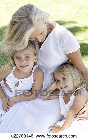 Stock Photograph - Grandmother cuddling her granddaughters. Fotosearch