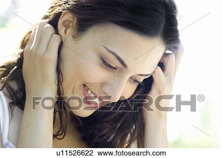 Stock Image - Happy woman holding her hair back. Fotosearch