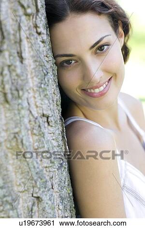 Happy woman leaning against a tree View Large Photo Image Stock Image - Happy woman leaning against a tree. Fotosearch