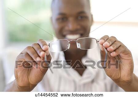 Man holding a pair of glasses View Large Photo Image Stock Image - Man holding a pair of glasses. Fotosearch
