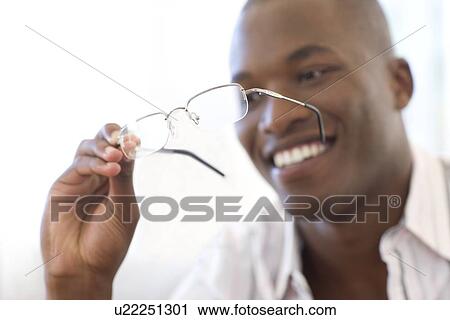 Stock Image - Man holding a pair of glasses. Fotosearch