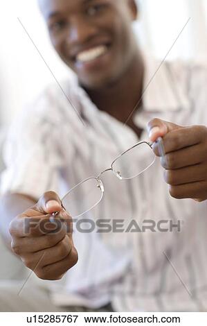Man holding a pair of glasses View Large Photo Image Stock Photo - Man holding a pair of glasses. Fotosearch