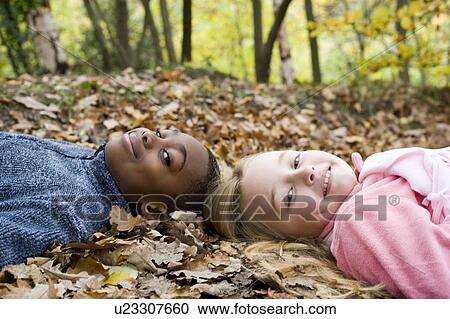 Smiling children lying on autumn leaves View Large Photo Image Stock Image - Smiling children lying on autumn leaves. Fotosearch