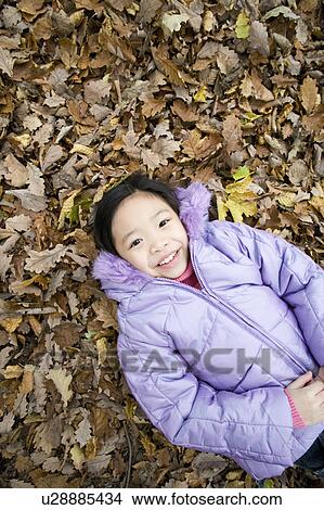 Smiling girl lying on autumn leaves View Large Photo Image Picture - Smiling girl lying on autumn leaves. Fotosearch
