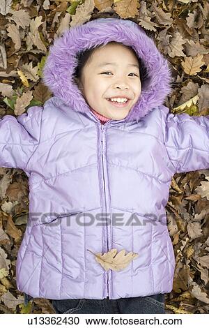 Smiling girl lying on autumn leaves View Large Photo Image Stock Image - Smiling girl lying on autumn leaves. Fotosearch