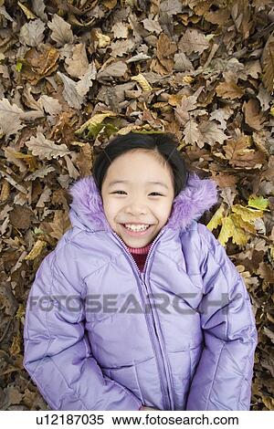 Smiling girl lying on autumn leaves View Large Photo Image Stock Photography - Smiling girl lying on autumn leaves. Fotosearch