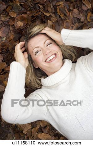 Smiling woman lying on autumn leaves View Large Photo Image Stock Image - Smiling woman lying on autumn leaves. Fotosearch