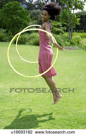 Stock Image - Woman playing with hula hoops. Fotosearch