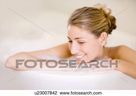 Stock Image - Woman relaxing in a bath. Fotosearch