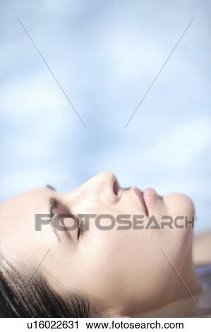 Stock Image - Woman relaxing in a swimming pool. Fotosearch