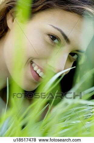 Stock Photo - Woman smiling through grass. Fotosearch