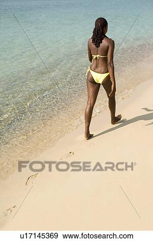 Stock Photo - Woman walking along a beach. Fotosearch