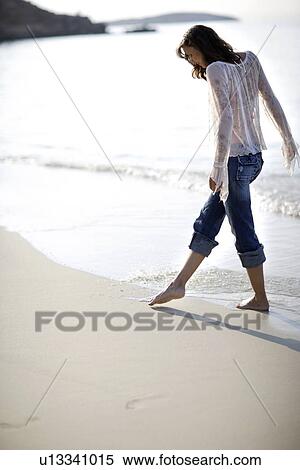 Stock Photography - Woman walking along a beach. Fotosearch