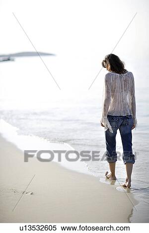 Stock Photography - Woman walking along a beach. Fotosearch