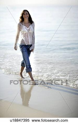 Woman walking along a beach View Large Photo Image Stock Photography - Woman walking along a beach. Fotosearch