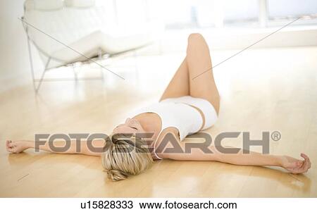 Stock Image - Young woman relaxing on the floor. Fotosearch