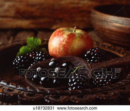 Stock Image - Apple, blackberries and blackcurrants in vintage wooden bowl with wooden spoon, close-up. Fotosearch