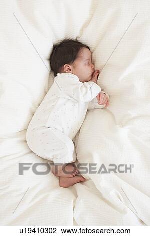 Stock Image - Baby asleep on bed. Fotosearch