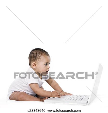 Stock Image - Baby girl playing with a laptop. Fotosearch