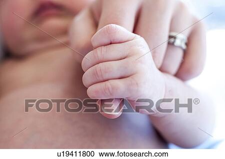 Stock Image - Baby holding mother's finger. Fotosearch