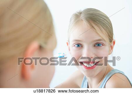 Stock Photograph - Bathroom mirror portrait of girl holding toothbrush. Fotosearch
