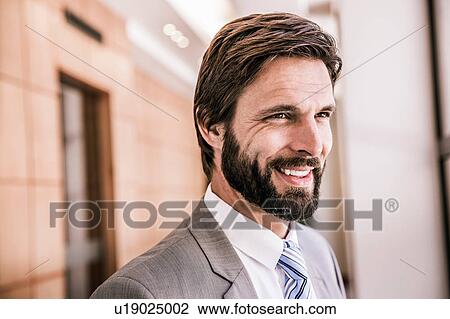Stock Image - Bearded business man looking away smiling. Fotosearch