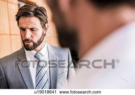 Stock Image - Bearded businessman looking down. Fotosearch