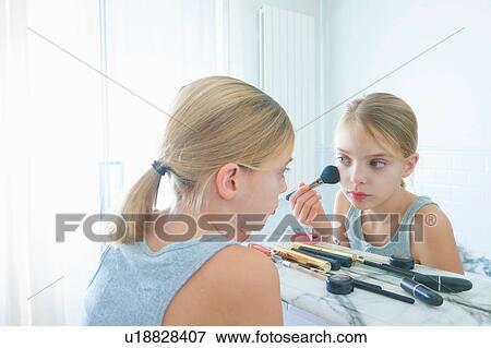 Stock Photo - Bedroom mirror image of girl applying blusher. Fotosearch