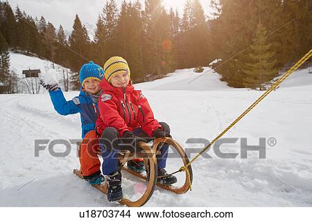 Picture - Boy and brother being pulled on toboggan in snow, Elmau, Bavaria, Germany. Fotosearch