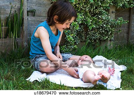 Boy tickling baby brother in garden View Large Photo Image Stock Image - Boy tickling baby brother in garden. Fotosearch
