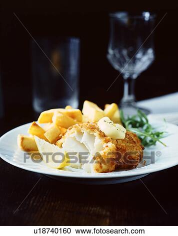Stock Image - Breaded fish with chips, rocket and lemon slice on white plate. Fotosearch