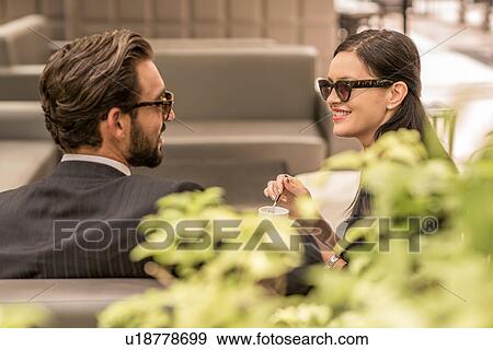 Stock Photo - Businessman and woman chatting on hotel garden sofa, Dubai, United Arab Emirates. Fotosearch