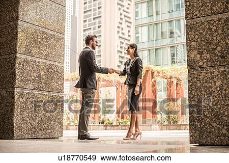 Businessman and woman shaking hands outside office, Dubai, United Arab Emirates View Large Photo Image Stock Photo - Businessman and woman shaking hands outside office, Dubai, United Arab Emirates. Fotosearch