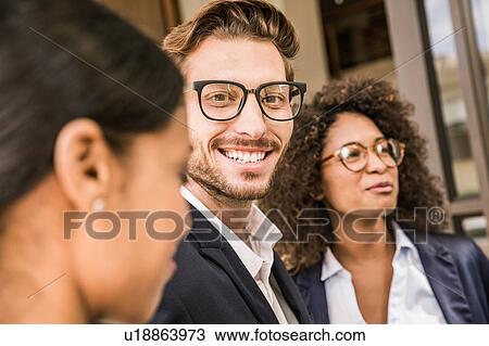Stock Image - Businessman and young businesswomen outside office. Fotosearch