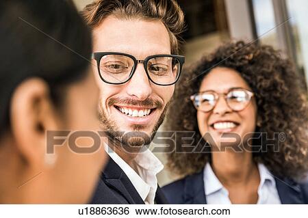 Stock Photograph - Businessman and young businesswomen talking outside office. Fotosearch