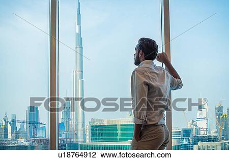 Businessman gazing through window with view of Burj Khalifa, Dubai, United Arab Emirates View Large Photo Image Stock Image - Businessman gazing through window with view of Burj Khalifa, Dubai, United Arab Emirates. Fotosearch