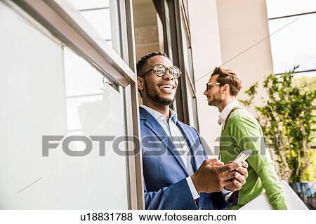 Businessman in office doorway using smartphone View Large Photo Image Stock Photo - Businessman in office doorway using smartphone. Fotosearch