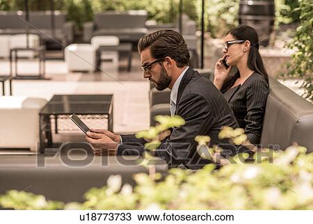 Businessman using digital tablet on hotel garden sofa, Dubai, United Arab Emirates View Large Photo Image Stock Image - Businessman using digital tablet on hotel garden sofa, Dubai, United Arab Emirates. Fotosearch