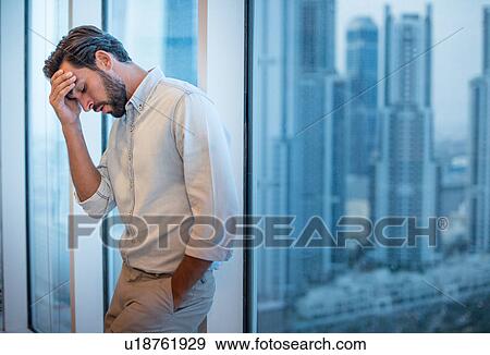 Businessman with hand on forehead at window with skyscraper view, Dubai, United Arab Emirates View Large Photo Image Stock Photo - Businessman with hand on forehead at window with skyscraper view, Dubai, United Arab Emirates. Fotosearch
