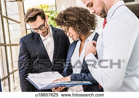 Stock Photography - Businessmen and businesswoman preparing paperwork outside office. Fotosearch