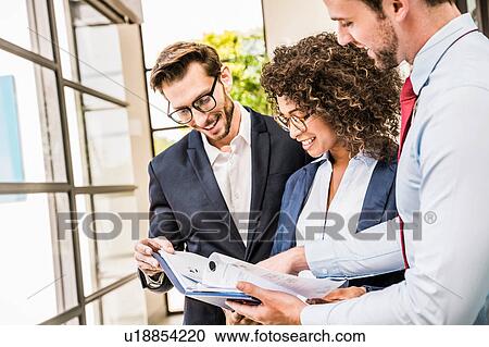 Businessmen and businesswoman reading paperwork outside office View Large Photo Image Stock Image - Businessmen and businesswoman reading paperwork outside office. Fotosearch