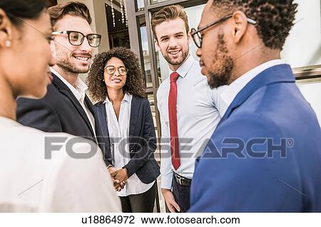 Stock Image - Businessmen and businesswomen having discussion outside office. Fotosearch