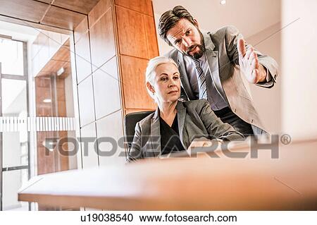 Businesspeople at desk looking at laptop having discussion View Large Photo Image Stock Image - Businesspeople at desk looking at laptop having discussion. Fotosearch