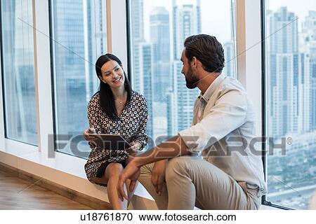 Businesswoman and man sitting at window with skyscraper view, Dubai, United Arab Emirates View Large Photo Image Stock Image - Businesswoman and man sitting at window with skyscraper view, Dubai, United Arab Emirates. Fotosearch