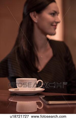 Stock Photo - Businesswoman sitting at hotel bar with coffee and digital tablet. Fotosearch