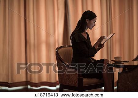 Stock Image - Businesswoman using digital tablet at hotel table. Fotosearch
