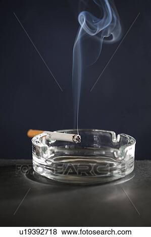 Stock Photo - Cigarette on ash tray with smoke. Fotosearch